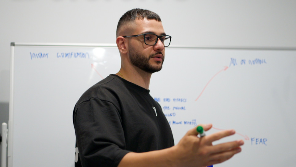 Man in black shirt standing in front of a whiteboard with notes.